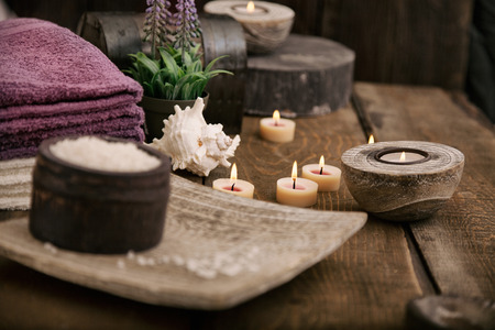 Spa and wellness setting with natural bath salt, candles, towels and flower. Wooden dayspa nature set