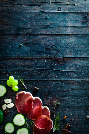 Italian ham, prosciutto and salami. Ingredients for bruschetta, crostini or sandwich bar. Rustic top view of ingredients. Ham with vegetables and spicesの写真素材