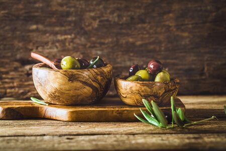 olives on olive branch. Wooden table with olives in bowlの写真素材