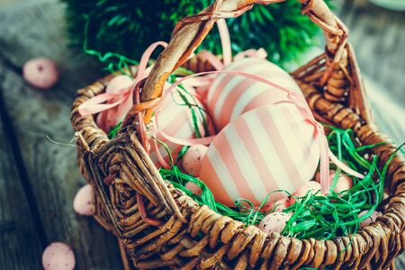 Colorful Easter holiday concept with pink eggs in wisker basket in nature