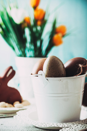 Easter. Chocolate  Eggs and bunny on Easter table. Tulips in vase. Easter setting  on tableの写真素材