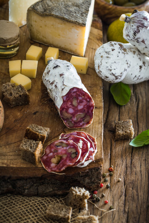 Cheese and Salami. Variety od cold cuts. Cheese on wood. Types of cheese and sausagesの写真素材