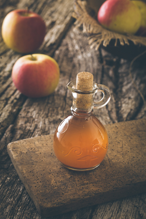 Apple vinegar. Bottle of apple organic vinegar on wooden background. Healthy organic food.の写真素材