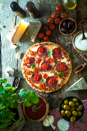 Fresh italian  pizza on wood. Pizza with cheese, salami and tomatoes. Fast food. Rustic pizzaの写真素材