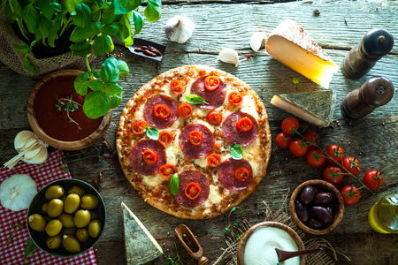 Fresh italian  pizza on wood. Pizza with cheese, salami and tomatoes. Fast food. Rustic pizzaの写真素材