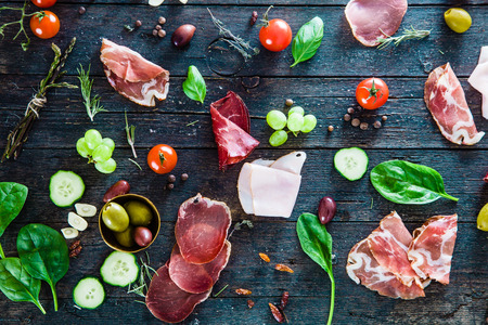 Italian ham, prosciutto and salami. Ingredients for bruschetta, crostini or sandwich bar. Rustic top view of ingredients. Ham with vegetables and spicesの写真素材