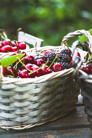 Fresh forest fruit on wood. Fresh organic fruit. Red cherries, blueberries and blackberriesの写真素材
