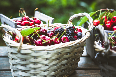 Fresh forest fruit on wood. Fresh organic fruit. Red cherries, blueberries and blackberriesの写真素材