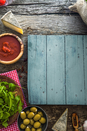 Wooden planks with food. Olives, basil, tomatoes and ingredients on woodの写真素材