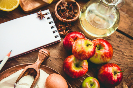 Baking background with paper for notes. Christmas and winter  cookies ingredients.Baking pastry and cookies: apples, spices, sugar, eggs on woodの写真素材