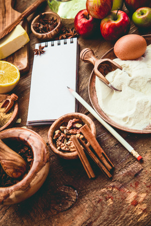 Baking background with paper for notes. Christmas and winter  cookies ingredients.Baking pastry and cookies: apples, spices, sugar, eggs on woodの写真素材