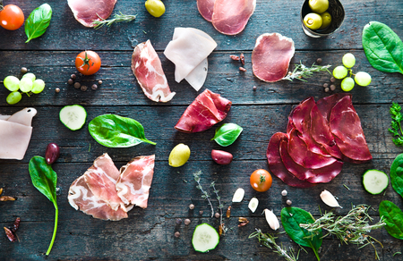 Italian ham, prosciutto and salami. Ingredients for bruschetta, crostini or sandwich bar. Rustic top view of ingredients. Ham with vegetables and spicesの写真素材