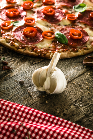 Fresh italian  pizza on wood. Pizza with cheese, salami and tomatoes. Fast food. Rustic pizzaの写真素材