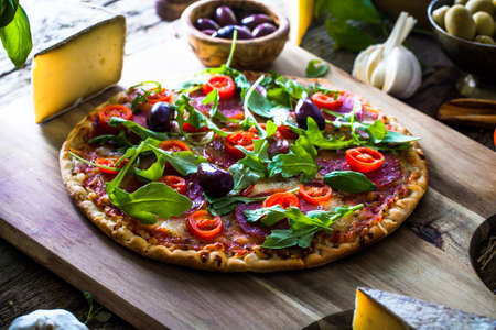 Fresh italian  pizza on wood. Pizza with cheese, salami and tomatoes. Fast food. Rustic pizzaの写真素材