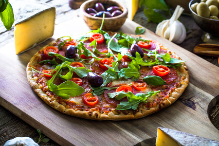 Fresh italian  pizza on wood. Pizza with cheese, salami and tomatoes. Fast food. Rustic pizzaの写真素材