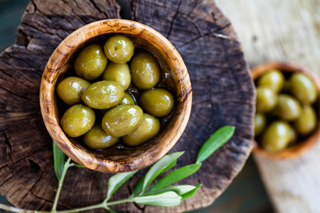 Fresh olives on rustic wooden background. Olives in olive wood.の写真素材