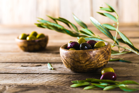 olives on olive branch. Wooden table with olives in bowlの写真素材
