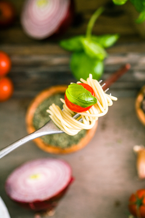 Italian cuisine. Pasta on fork. Pasta with olive oil, garlic, basil and tomatoes. Spaghetti with tomatoesの写真素材