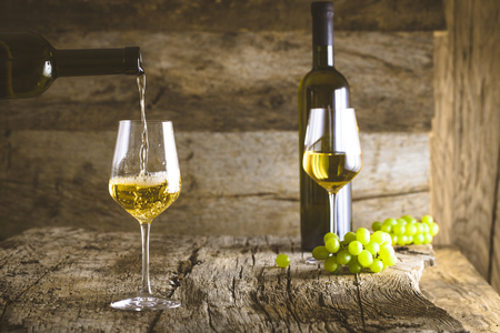 Wine. Glass of white wine in wine cellar. Old white wine on wood.の写真素材