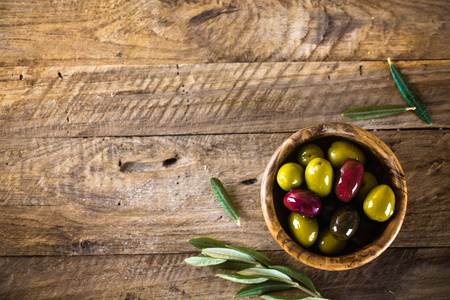 olives on olive branch. Wooden table with olives in bowlの写真素材