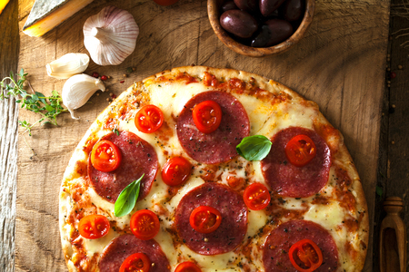 Fresh italian  pizza on wood. Pizza with cheese, salami and tomatoes. Fast food. Rustic pizzaの写真素材