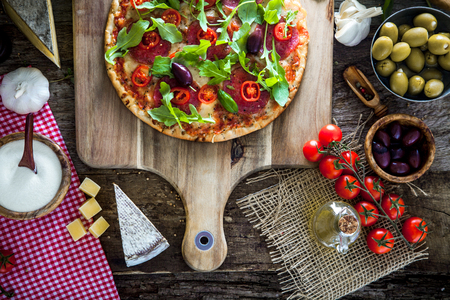 Fresh italian  pizza on wood. Pizza with cheese, salami and tomatoes. Fast food. Rustic pizzaの写真素材