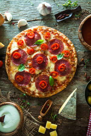 Fresh italian  pizza on wood. Pizza with cheese, salami and tomatoes. Fast food. Rustic pizzaの写真素材