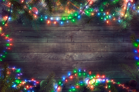 Christmas fairy lights on wood. Christmas background with string lights and pine tree. Fir branchesの写真素材