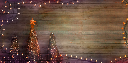 Christmas trees on wood. Christmas greeting card. Rustic Xmas with fairy lightsの写真素材
