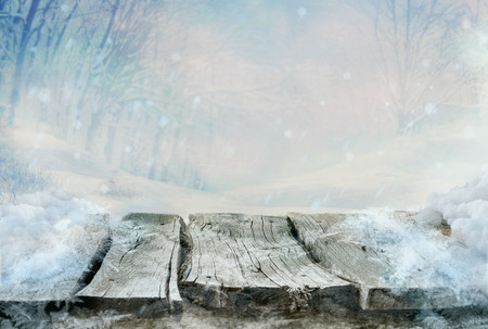 Winter design. Christmas background with frozen wooden table with the landscape. Snow and ice on wooden table with snowy forestの写真素材