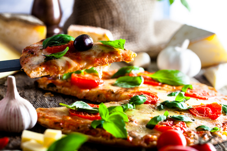 Pizza on wood with ingredients. Pizza with cheese, tomatoes and basil. Rustic italian pizzaの写真素材