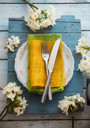Spring table setting. Narcissus flower. Fork and knife on Easter table. Holiday table setting. Top flatlay ovehead viewの写真素材