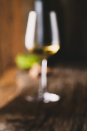 Blurred shot of wine glass. Glass of white wine in wine cellar. Old white wine on wood.の写真素材