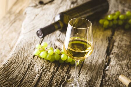 Wine. Glass of white wine in wine cellar. Old white wine on wood.の写真素材