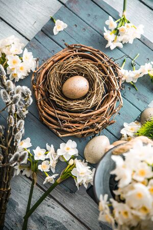Easter eggs on wood. Natural quail eggs. Easter holiday concept with  eggs in wisker basket in natureの写真素材