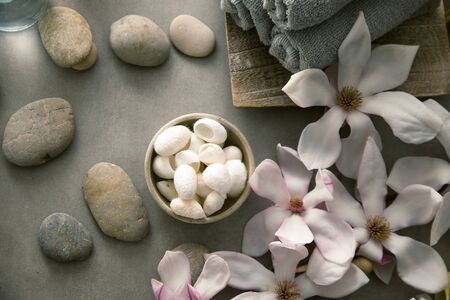 Spa and wellness. Natural massage stones , silkworm cocoon with magnolia flower .Spa treatmentの写真素材
