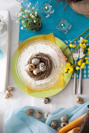 Easter table setting with quail eggs and spring flowers on the tableの写真素材