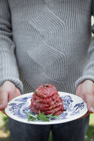 Man is holding burgers for BBQ. Barbecue burgersの写真素材