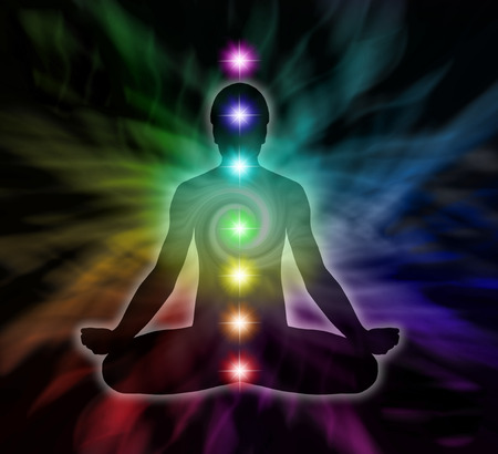 Silouette of a man in lotus meditation position with Seven Chakras on flowing rainbow energy backgroundの写真素材