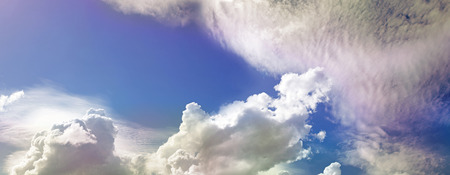 Wide blue sky and random clouds with pink tingesの写真素材