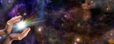 Wide deep space banner with male hands cupped and a rainbow colored spark between 