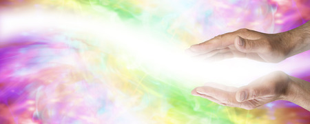 Male parallel healing hands with light wave passing on colored banner backgroundの写真素材