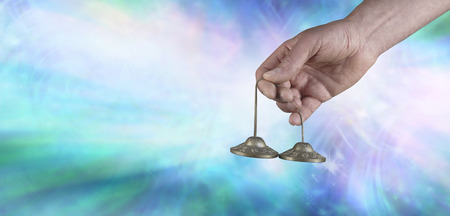 Ting Sha sound vibrations - Male Sound healer holding Ting Sha percussion bells against a blue background with white light depicting sound vibrationsの写真素材