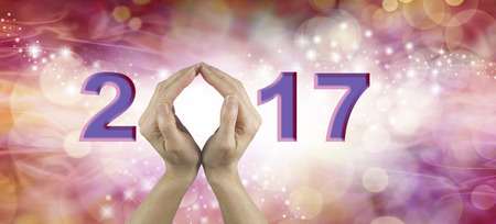 Welcome 2017 with both hands - Female using both hands to make an O in the word 2017 on a warm red and pink colored starry bokeh  backgroundの写真素材