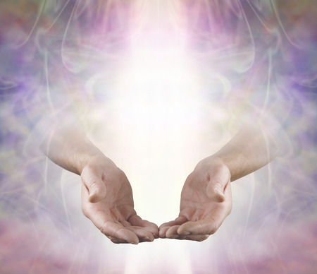 Offering You Angelic Love and Healing - male open hands emerging from beautiful muted color energy field background with a shaft of white light and plenty of copy space aboveの写真素材