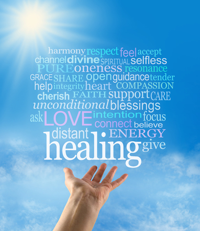 Sending out beautiful healing intention - female hand palm up with a large HEALING word floating above and a word cloud on a blue sky background with a sunburst and sun rays beaming downの写真素材