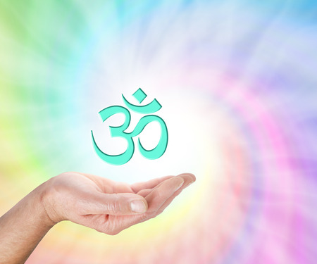 Offering Om Symbol - male hand with palm facing up and a light green OM symbol floating above on a rainbow colored spiral background and copy spaceの写真素材