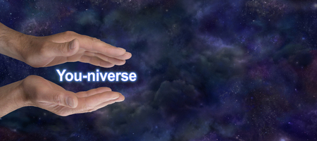 You are connected to ALL THAT IS - a pair of male parallel hands with You-niverse floating between on a dark starry night sky background with copy spaceの写真素材
