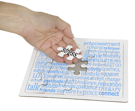 Stress Management Puzzle Word Cloud -  a hand holding the final jigsaw piece over a jigsaw puzzle  showing a word cloud containing words relevant to stress managementの写真素材
