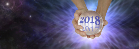 Ask a fortune teller for a 2018 reading -  pair of hands holding a large crystal ball showing 2018 fading out 2017 on a deep space background with a burst of energy behindの写真素材